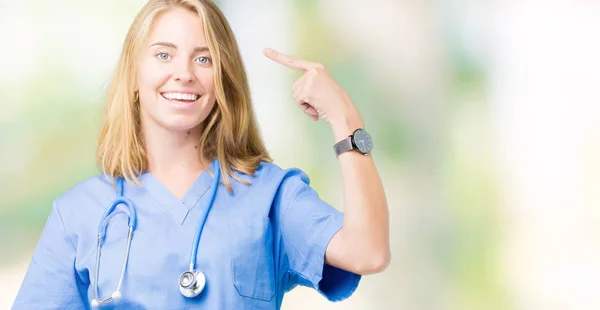 美丽的年轻医生妇女穿着医疗制服在孤立的背景微笑 用一个手指指着头 伟大的想法或想法 良好的记忆力 — 图库照片