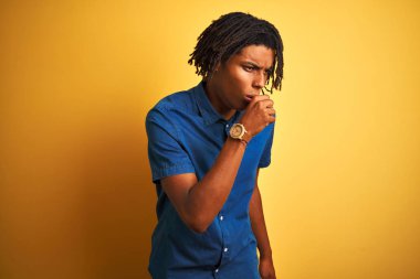 Düzensiz sarı arka plan hissi üzerinde ayakta rahat denim gömlek giyen dreadlocks ile Afro adam ve soğuk veya bronşit için belirti olarak öksürük. Sağlık konsepti.