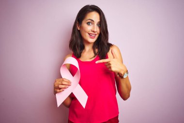 Genç güzel kadın tutan kanser şerit üzerinde pembe izole arka plan çok mutlu işaret ile el ve parmak