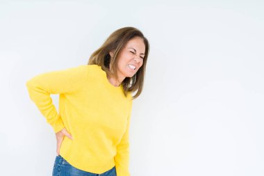 Izole arka plan üzerinde sarı kazak giyen güzel orta yaş kadın sırt ağrısı acı, el ile geri dokunmadan, kas ağrısı