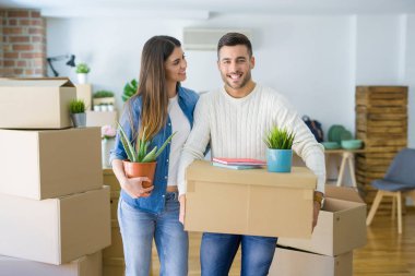 Güzel genç çift yeni bir ev, yeni bir dairede mutlu tutan karton kutular gülümseyen hareket