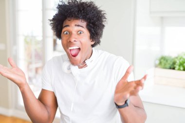 Afrikalı Amerikan adam kulaklık müzik deli kutluyor ve silah ile başarı için hayran dinleme giyiyor kaldırdı ve açık gözleri heyecanlı çığlık. Kazanan kavramı