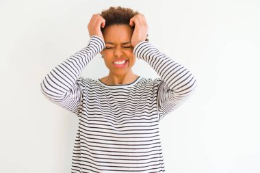 Genç güzel Afrikalı Amerikalı kadın baş ağrısı umutsuz ve ağrı ve migren nedeniyle vurguladı beyaz arka plan üzerinde çizgili kazak giyiyor. Eller baş.