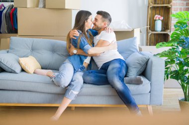 Kanepede aşık güzel çift sarılmak, çok mutlu yeni ev için heyecanlı gülümseyen