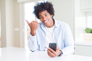 Afrikalı Amerikan adam akıllı telefon işaret ve mutlu yüz gülümseyen yan başparmak ile gösteren kullanarak