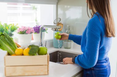 Genç kadın lavabo su kullanarak sebze ve meyve yıkama