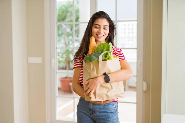 Mooie jonge vrouw glimlachend een papieren zak vol vers — Stockfoto