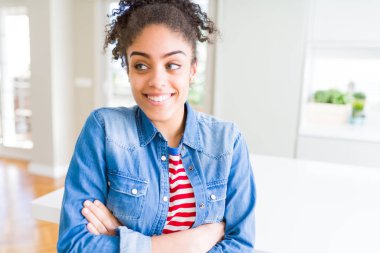 Afro saçlı rahat denim ceket görünümlü yan ve dik dik bakma uzağa düşünce gülümseyen güzel genç Afro-Amerikan kadın.