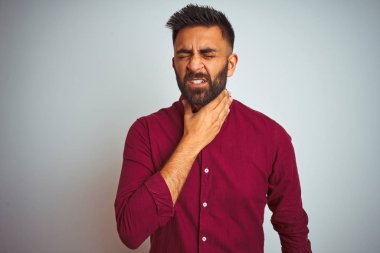 İzole gri arka planda ayakta kırmızı zarif gömlek giyen genç Hintli adam ağrılı boyun dokunmadan, grip için boğaz ağrısı, kesek ve enfeksiyon