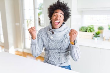 Afrika Amerikan adam çok mutlu ve heyecanlı silah ile kazanan jest yapıyor kış kazak giyiyor, gülümseyen ve başarı için çığlık kaldırdı. Kutlama konsepti.