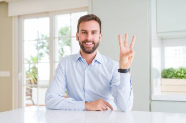 Yakışıklı iş adam gösteren ve parmaklar üç numara ile işaret ederken emin ve mutlu gülümseyen.