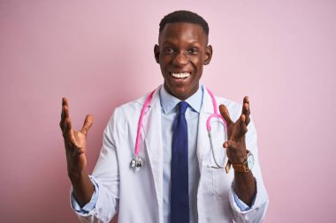Izole pembe arka plan üzerinde duran stetoskop giyen Afro-Amerikan doktor adam kollarını kaldırdı ve kapalı gözleri heyecan çığlık ile başarı için deli ve deli kutluyor. Kazanan kavramı