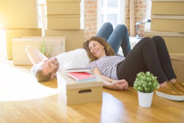 Orta yaş Senior romantik çift yerde yatıyor, yeni bir eve hareket için mutlu gülümseyen, rahatlatıcı ve ambalaj kutularının bir mola alarak