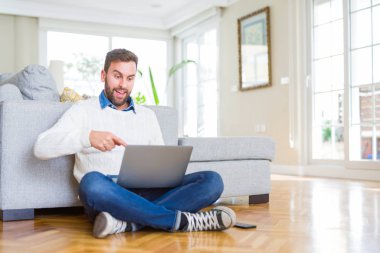 Yakışıklı adam bilgisayar laptop kullanarak çalışma giyen çok mutlu el ve parmak ile işaret