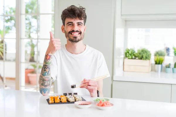 Młody Człowiek Jedzenia Asian Sushi Dostawą Domu Zadowolony Wielkim Uśmiechem — Zdjęcie stockowe