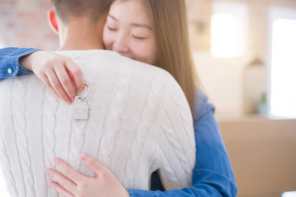 Young asian couple holding keys of new house, smiling happy and