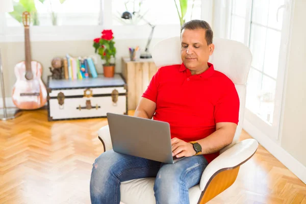 Middle age man using laptop sitting on the couch at home