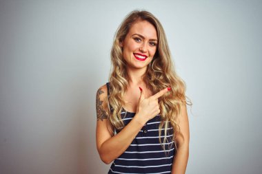 Çizgili t-shirt giyen genç güzel kadın mutlu ve doğal ifade ile yan yana el ve parmak ile işaret yüzünde bir gülümseme ile neşeli beyaz izole arka plan üzerinde duran