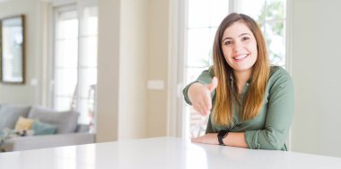 Evde güzel genç kadın tebrik ve davetkar olarak dostu sunan el sıkışması gülümsüyor. Başarılı iş.