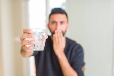 Yakışıklı İspanyol adam hata için utanç ile şok eli ile su kapağı ağız taze bir bardak içme, korku ifadesi, sessizlik, gizli kavram korkmuş