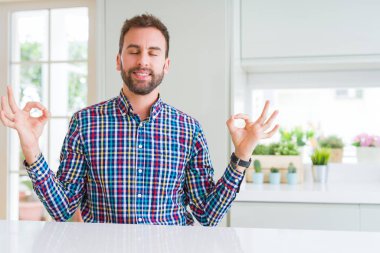 Renkli gömlek giymiş yakışıklı adam rahatla ve gülümseyen gözlerle kapalı parmak jestle meditasyon yapıyor. Yoga kavramı.