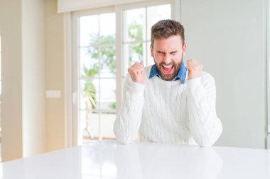 Rahat kazak giyen yakışıklı adam silah ile başarı için heyecanlı gülümseme kutluyor kaldırdı. Kazanan kavramı.