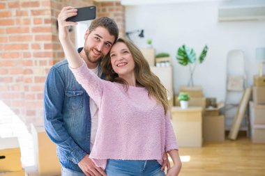 Yeni bir eve taşımak için çok mutlu gülümseyen Smartphone kullanarak bir selfie fotoğraf çekerken genç güzel çift