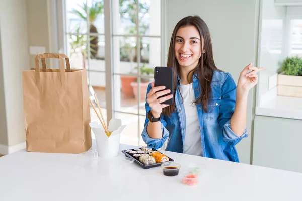 手と指を横に指差して非常に幸せなスマートフォンを使用してアプリから食品配達を注文する美しい若い女性 — ストック写真