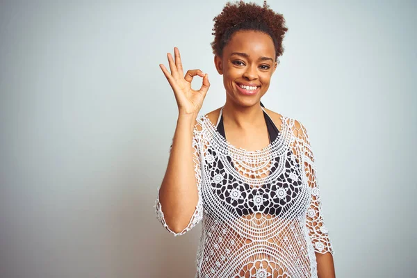 Young african american woman with afro hair wearing a bikini over white isolated background smiling positive doing ok sign with hand and fingers. Successful expression.