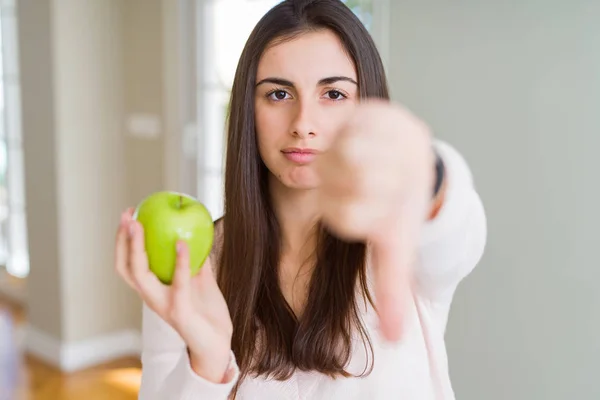 美丽的年轻女子吃健康的绿色苹果水果与愤怒的脸 负面标志显示不喜欢用拇指向下 拒绝概念 — 图库照片