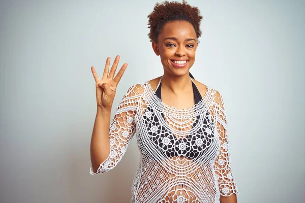 Young african american woman with afro hair wearing a bikini over white isolated background showing and pointing up with fingers number four while smiling confident and happy.