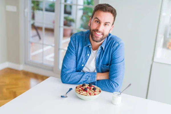 Hombre guapo desayunando comiendo cereales en casa y sonriendo — Foto de Stock