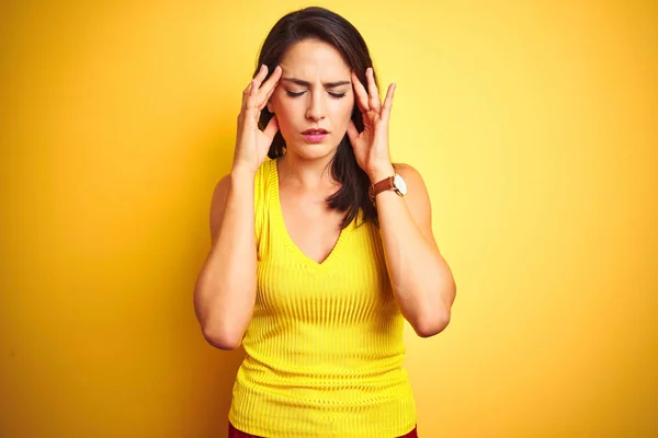 ストレスのため頭の痛みに頭を抱えた黄色の孤立した背景の上に立つTシャツを着た若い美しい女性 苦しむ片頭痛 — ストック写真