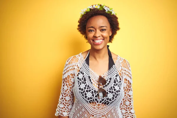 Young african american woman with afro hair wearing flowers crown over yellow isolated background with a happy and cool smile on face. Lucky person.