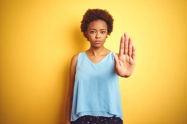 孤立した黄色の背景の上にエレガントなシャツを着た美しいアフリカ系アメリカ人女性は 手のひらで歌うのをやめます 顔に否定的で深刻なジェスチャーを伴う警告表現 — ストック写真