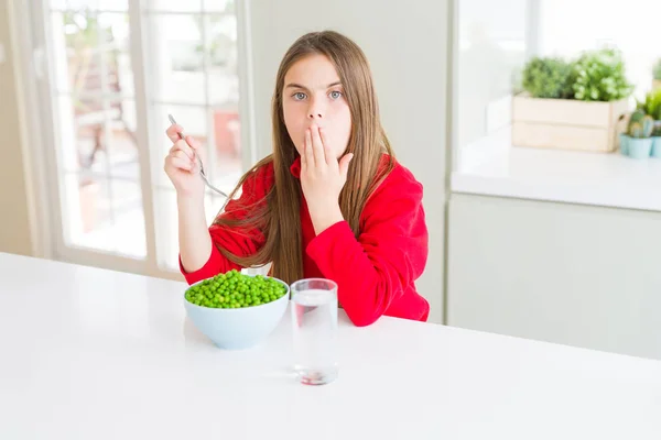 美丽的年轻女孩吃健康的绿色豌豆盖嘴与手震惊与耻辱的错误 表达恐惧 害怕在沉默 秘密概念 — 图库照片