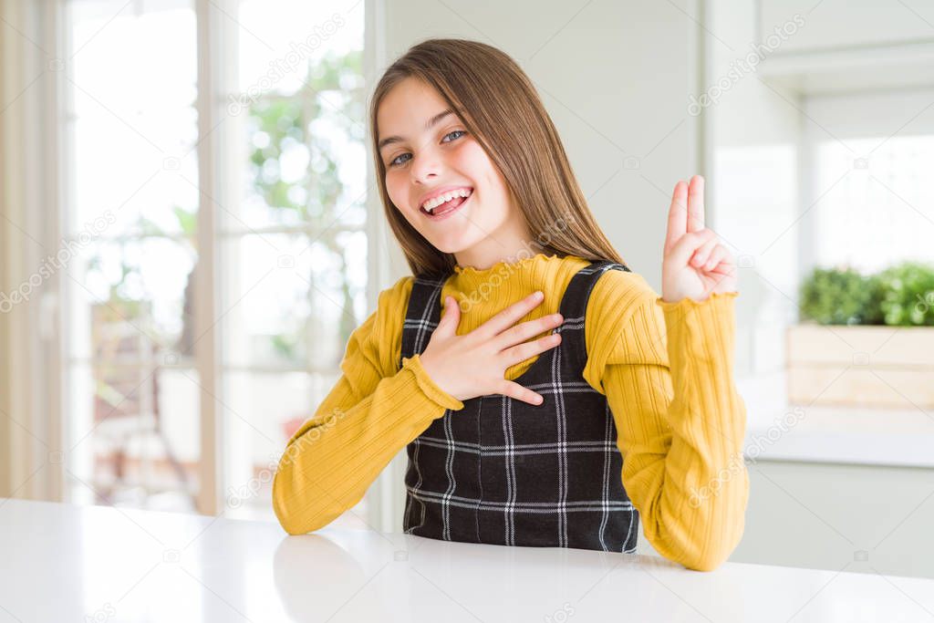 Young beautiful blonde kid girl wearing casual yellow sweater at home smiling swearing with hand on chest and fingers up, making a loyalty promise oath