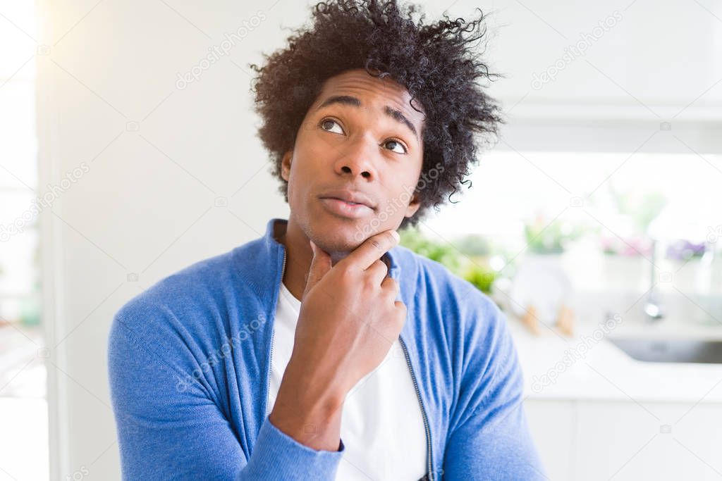 African American man at home with hand on chin thinking about question, pensive expression. Smiling with thoughtful face. Doubt concept.