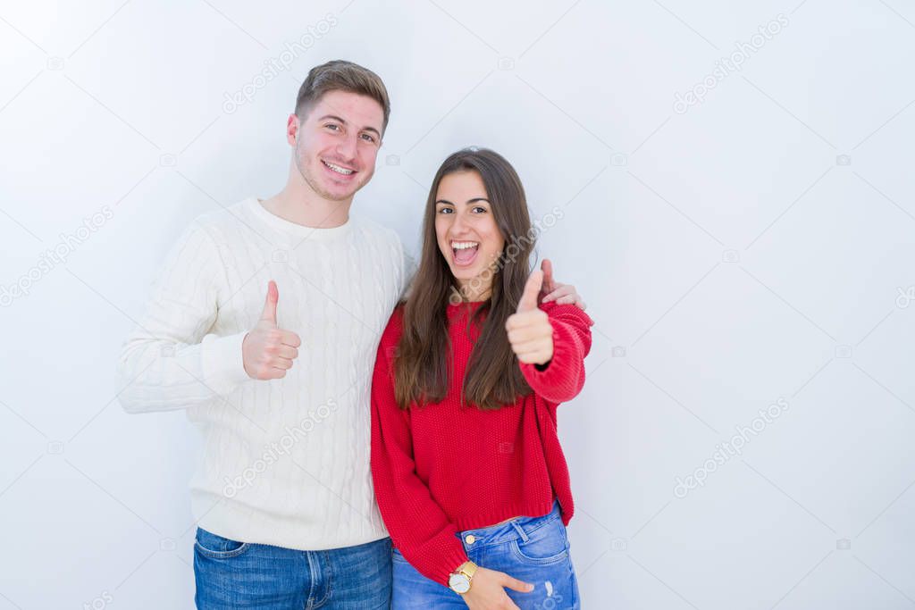 Beautiful young couple over white isolated background doing happy thumbs up gesture with hand. Approving expression looking at the camera with showing success.