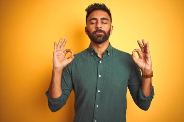 Genç Hint işadamı izole beyaz arka plan üzerinde ayakta zarif gömlek giyiyor Relax ve gözleri ile gülümseyen meditasyon jest parmaklar ile kapalı. Yoga konsepti.