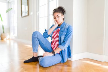 Afro saç ile güzel genç Afrikalı Amerikalı kadın yerde oturan düşünme yorgun ve çapraz silah ile depresyon sorunları ile sıkılmış bakıyor.