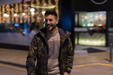 Yakışıklı delikanlı possing ve gülümseyerek. Geceleri sokak stili