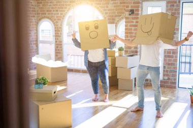 Komik emoji ile karton kutular giyen çılgın çift kafa üzerinde yüzler, yeni evde eğlenmek