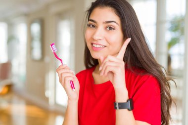 Diş diş fırçası tutan genç kadın bir fikir veya soru mutlu yüz, bir numara ile parmak işaret ile şaşırttı