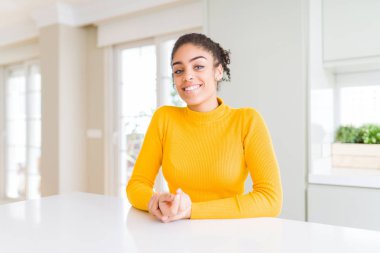 Afro saç ile güzel Afrikalı Amerikan kadın birlikte eller ile rahat bir sarı kazak giyiyor ve parmaklar rahat ve neşeli gülümseyen geçti. Başarı ve iyimserlik