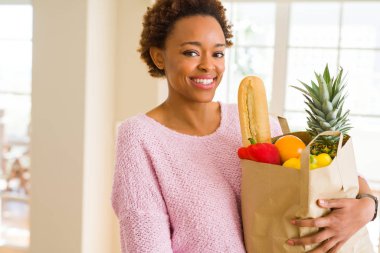 Kağıt torba dolu tutan genç güzel Afrikalı-Amerikalı kadın