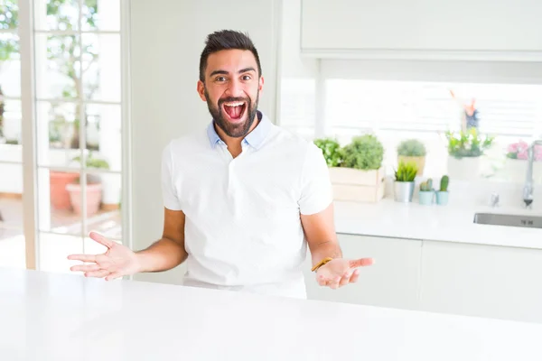 英俊的西班牙男人随意的白色 T恤在家里庆祝疯狂和惊讶的成功与手臂抬起和睁开眼睛尖叫兴奋 优胜者概念 — 图库照片