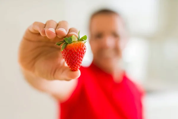 Cerca de hombre de mediana edad sosteniendo fresa — Foto de Stock
