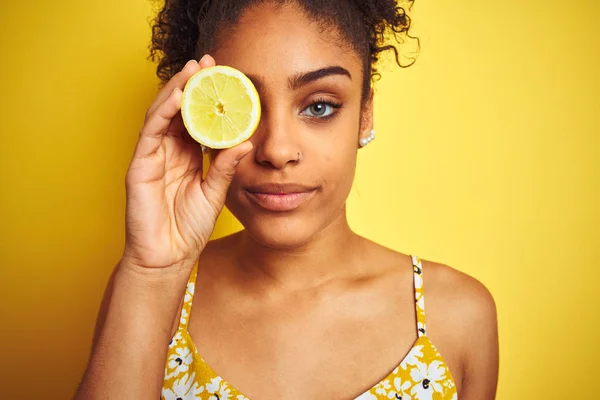 孤立した黄色の背景の上にレモンのスライスを保持する若いアフリカ系アメリカ人女性は 真剣に考えるスマートな顔に自信のある表情で — ストック写真