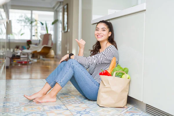 Jonge Vrouw Zittend Keukenvloer Met Een Papieren Zak Vol Verse — Stockfoto